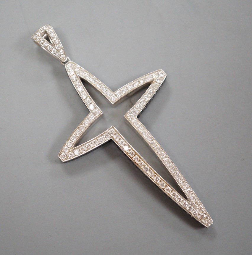 A modern 750 white metal, pave set white and black diamond set stylised cross pendant, overall 59mm, gross weight 12.7 grams.